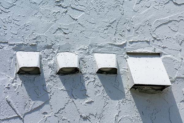 Dryer Vent Cleaning - Advance Chimney Four dryer vent exhausts on stucco home