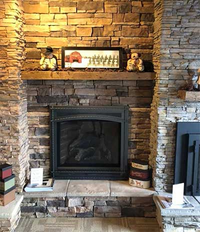 Black fireplace insert -- Advance Chimney Specialist Beautiful black fireplace insert surround by stacked stone with a decorated wooden mantel