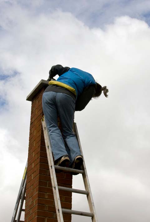 Chimney tech on ladder inspecting tall chimney