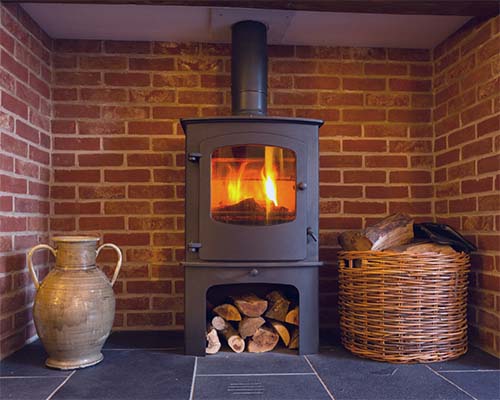 Modern black wood stove with fire in top and wood storage in bottom basket and urn decoration